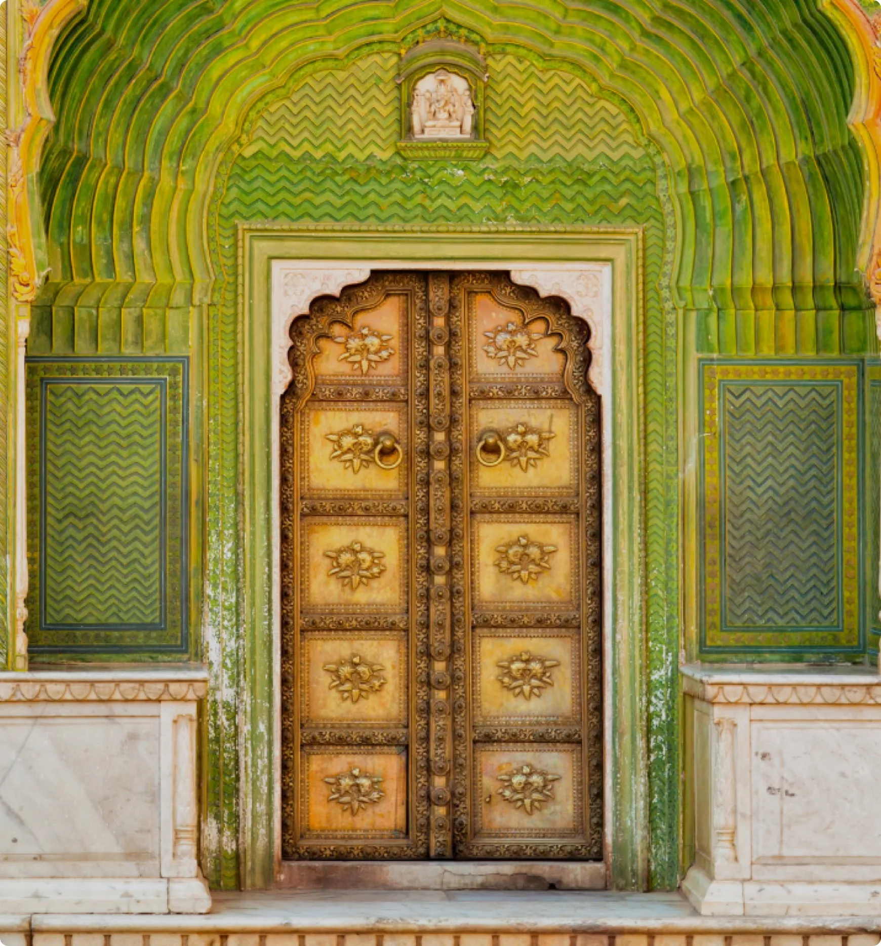 Ornate carved wooden door in a green arched doorway