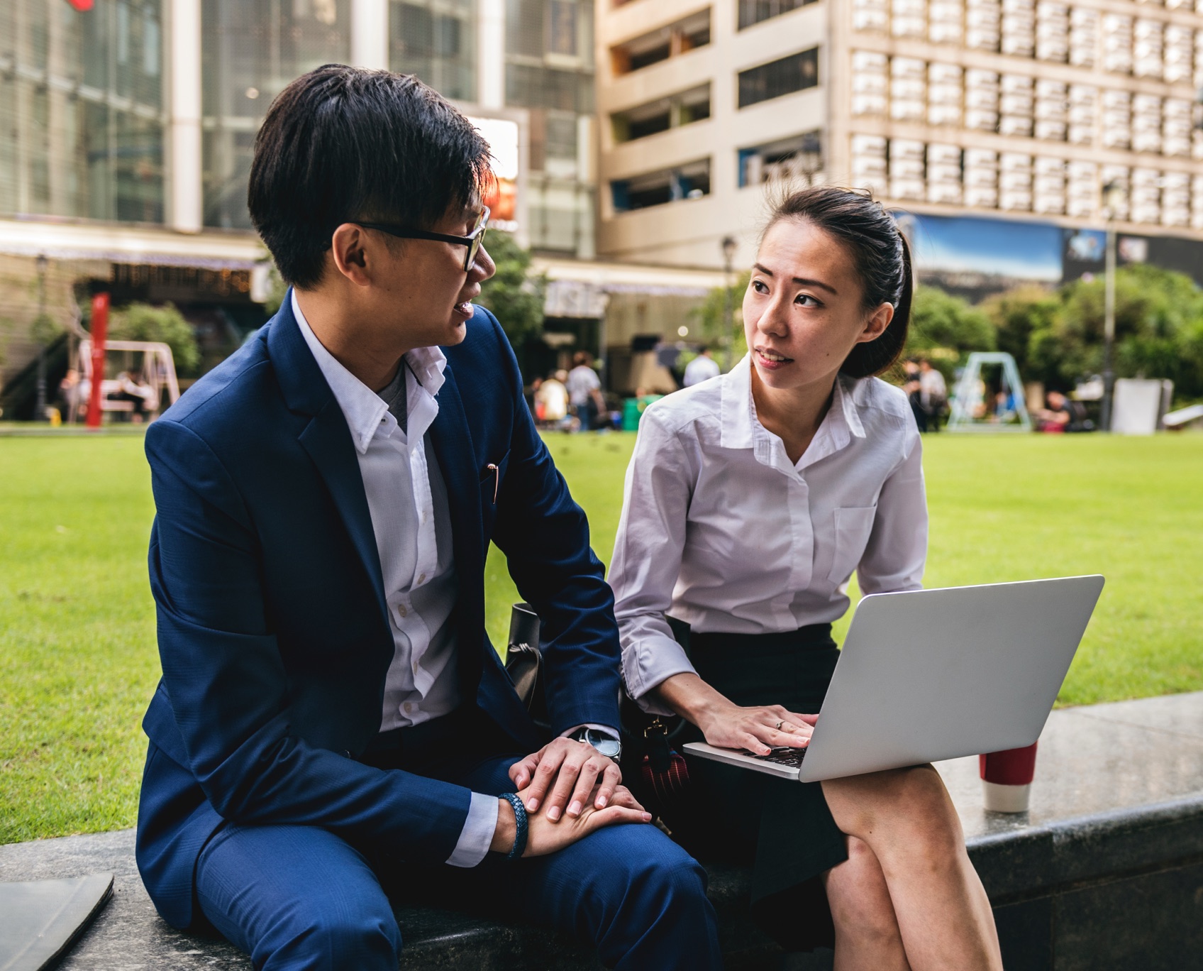 Two colleagues talking over a laptop outdoors